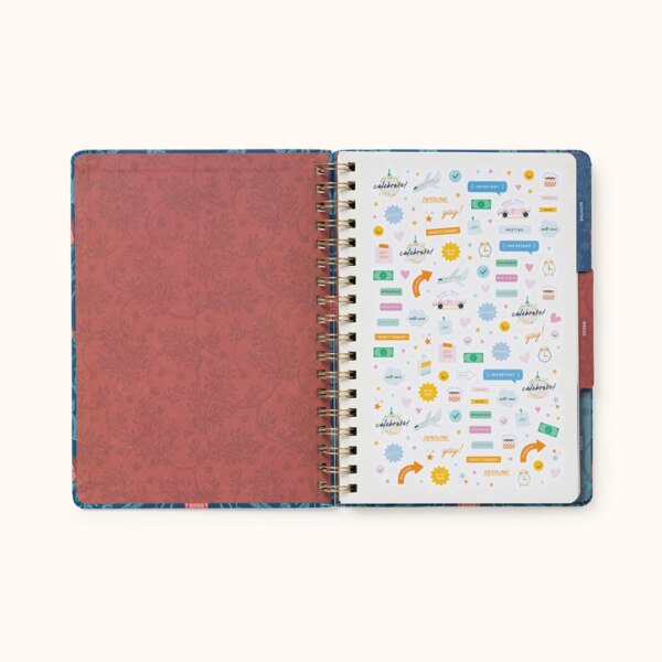 Notebook open showing inside of cover to be a red with a deeper red of the flower design from the front, showing the first page including stickers